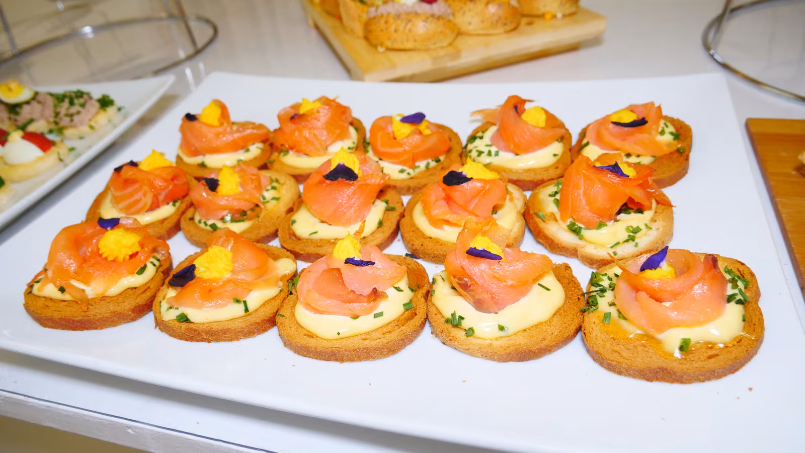 Blinis au saumon fumé, crème et fleurs comestibles sur un plat blanc