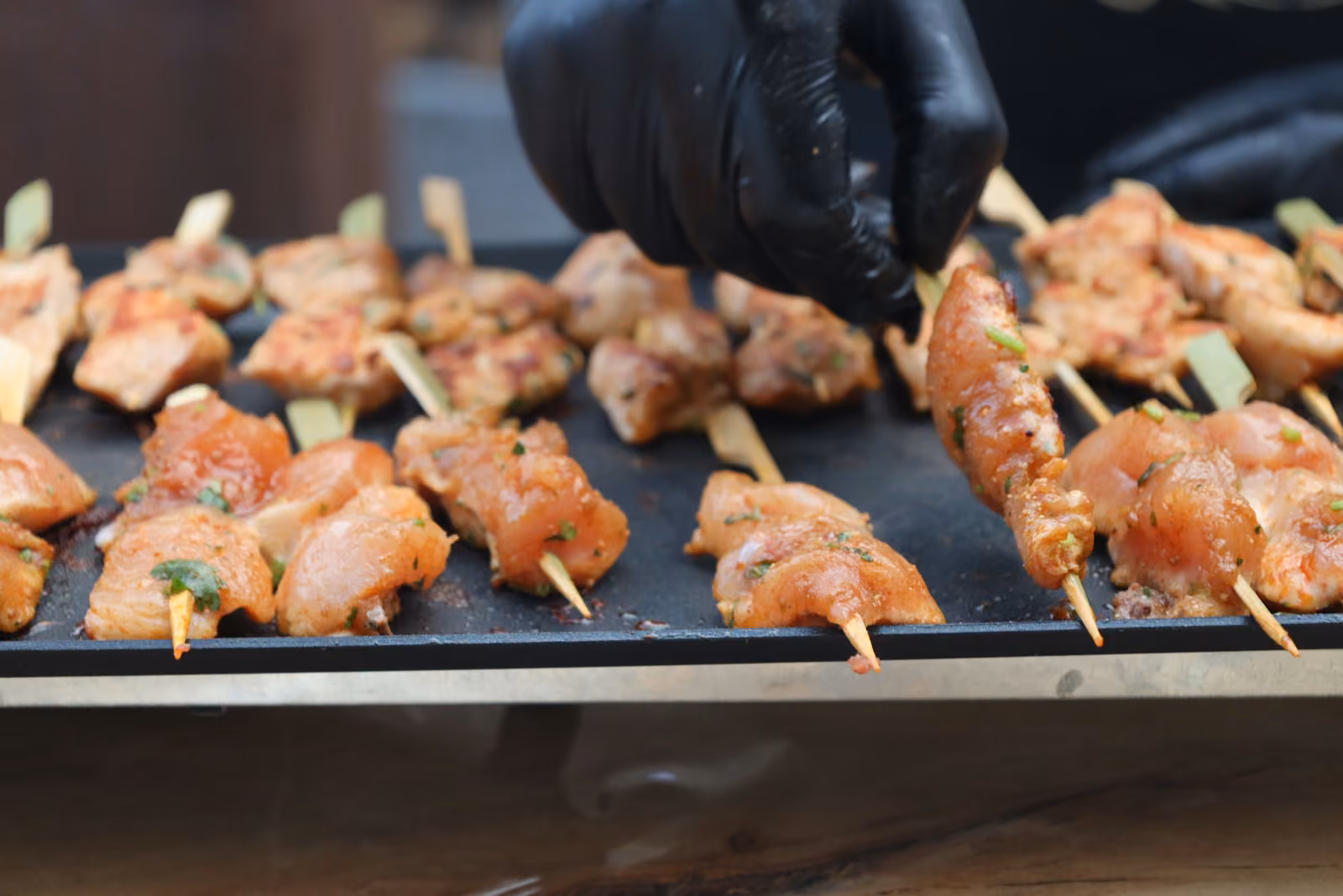 Brochettes de poulet mariné aux épices en train de griller sur une plancha