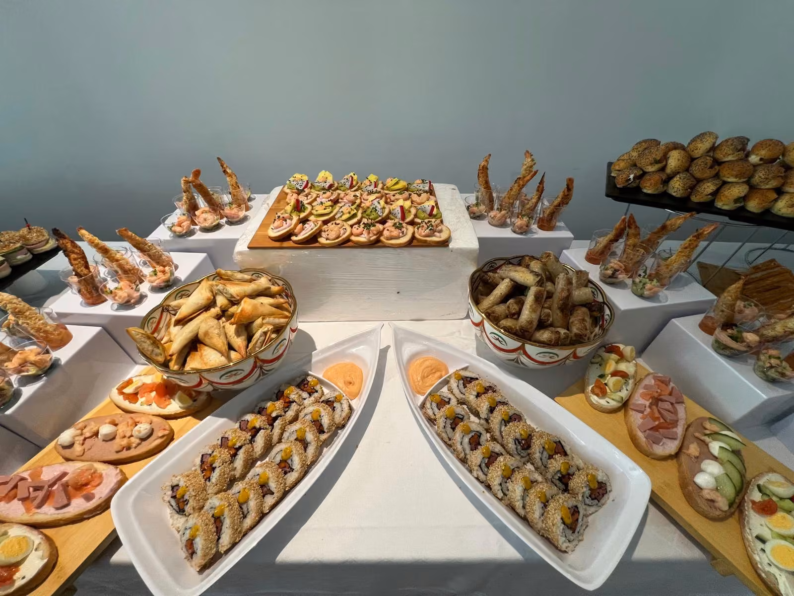 Buffet dînatoire en salle lumineuse : makis, briouates, crevettes, canapés et tartines