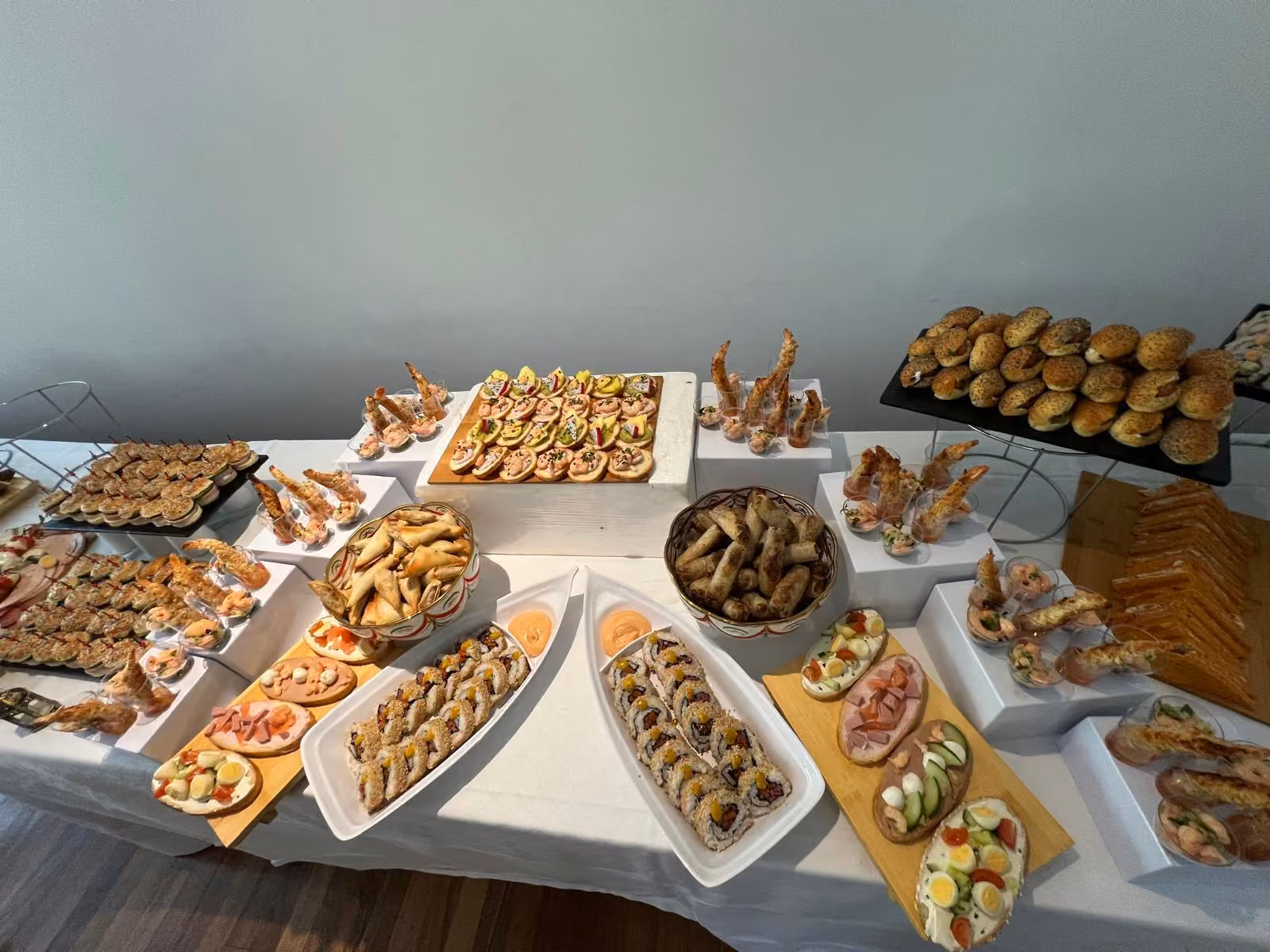 Vue d'ensemble d'un buffet dînatoire : plats en V de makis, briouates, crevettes et canapés