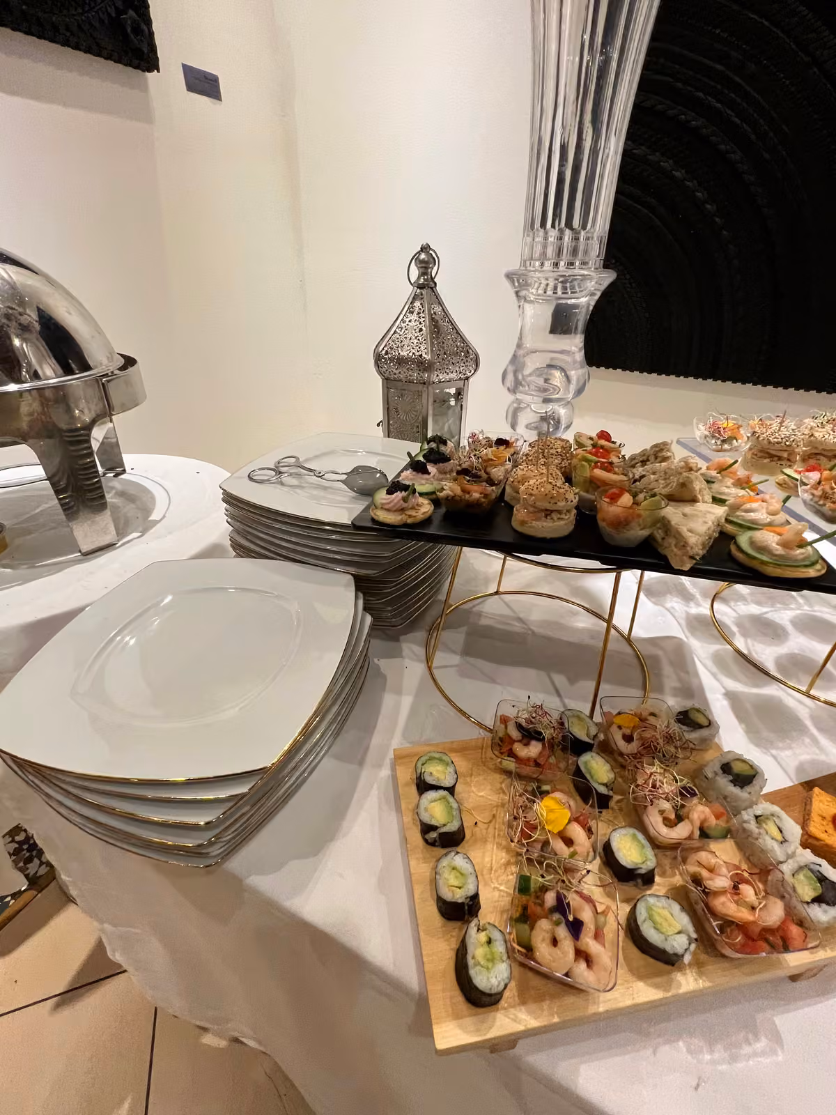 Plateau de makis et de crevettes à côté d'une lanterne orientale et d'une pile d'assiettes