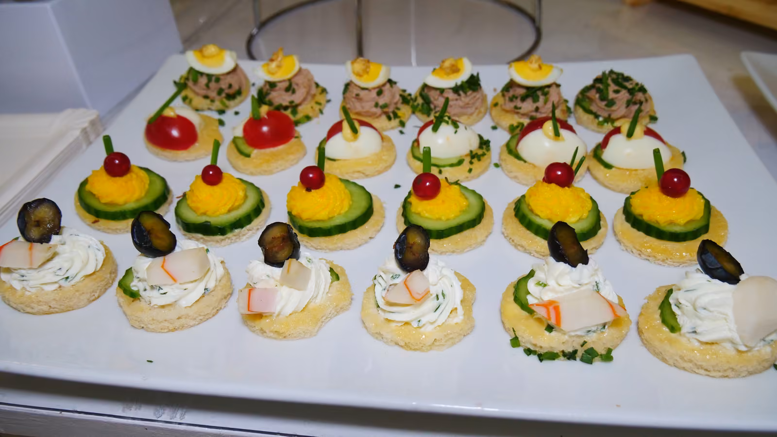 Canapés ronds à l'œuf mimosa, au thon et aux légumes sur un plat blanc