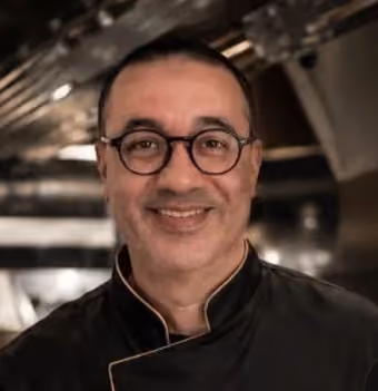 Le chef de Mariage Traiteur Paris, en veste de cuisine noire, dans sa cuisine