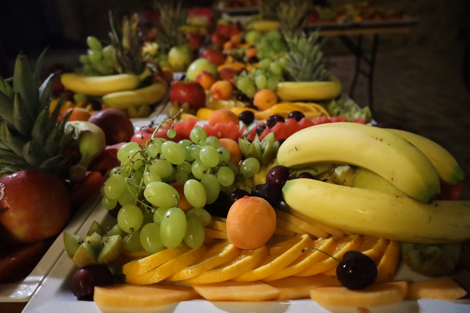 Gros plan d'un plateau de fruits : bananes, raisin blanc, abricot et tranches d'orange