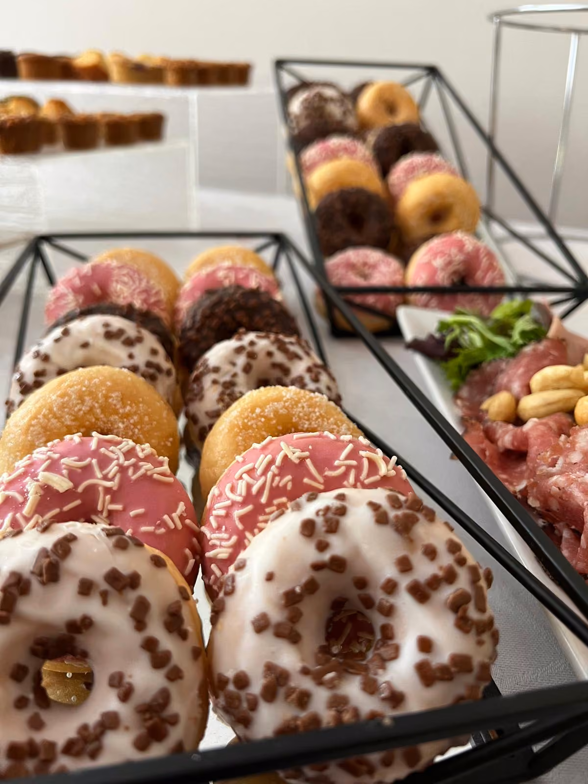 Donuts glacés roses et chocolat sur un présentoir en métal noir