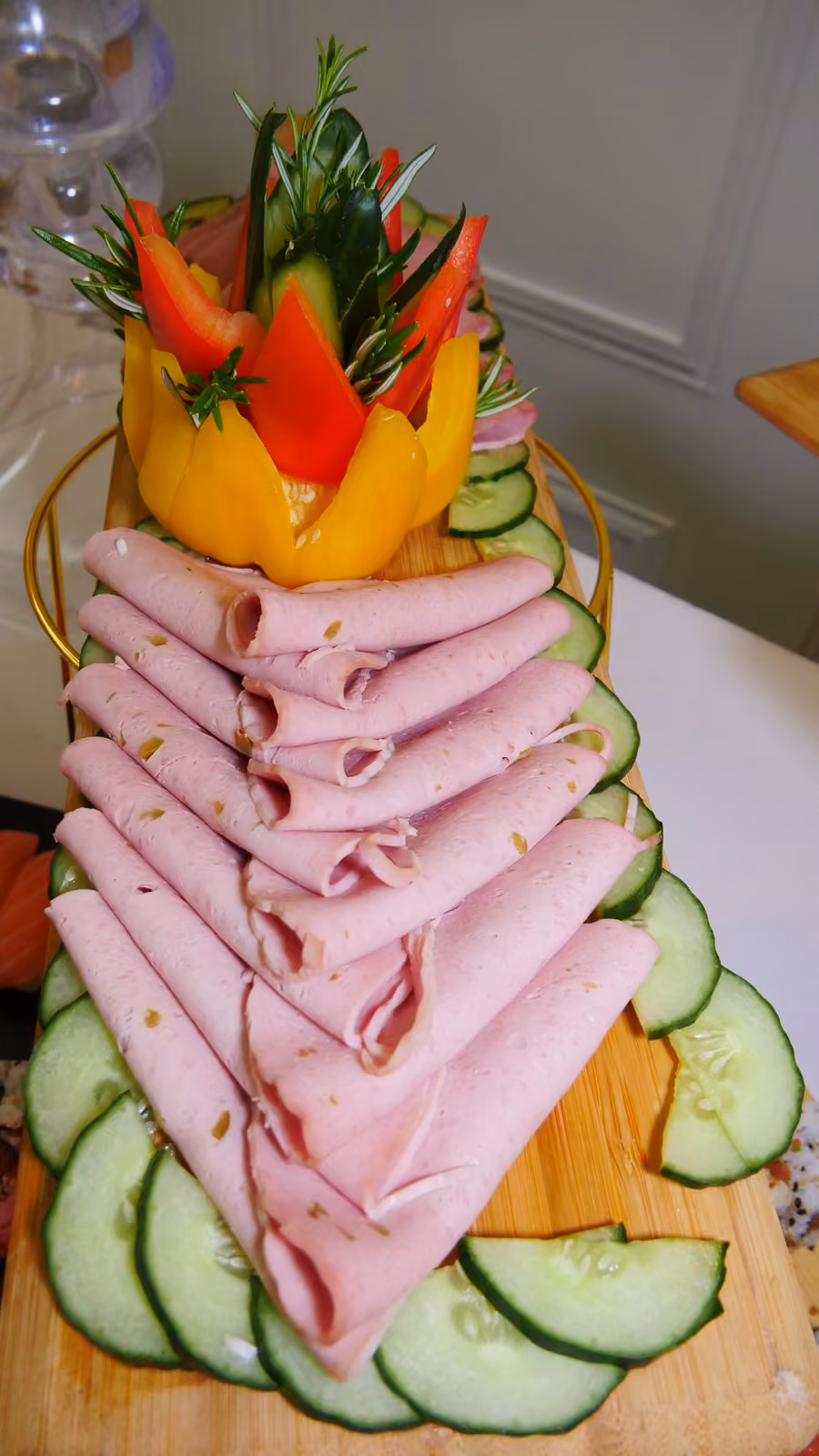 Tranches de jambon roulées en éventail, décor de poivron et rondelles de concombre sur planche