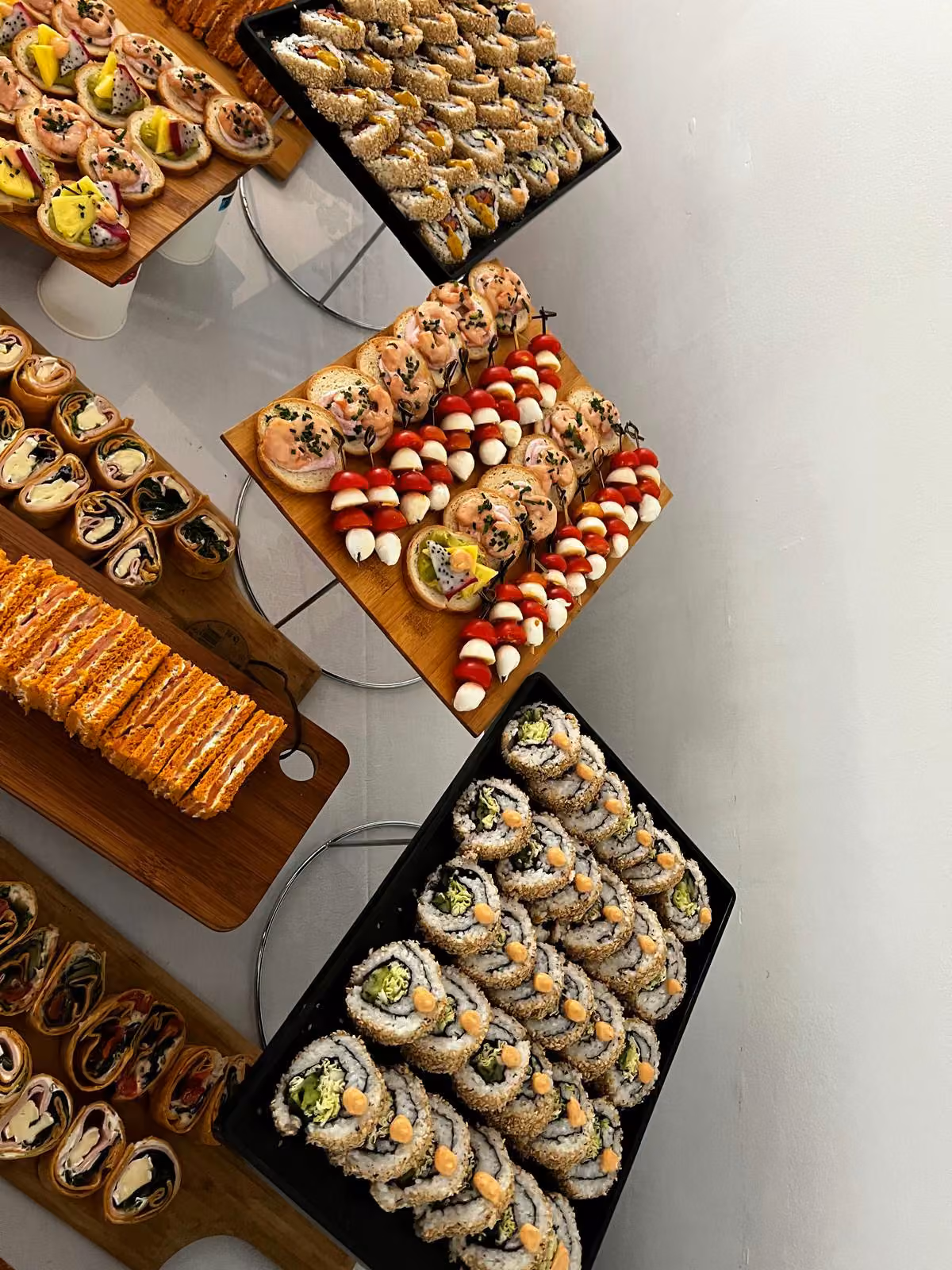Makis alignés sur ardoise et brochettes de tomate cerise et mozzarella sur plateau en bois