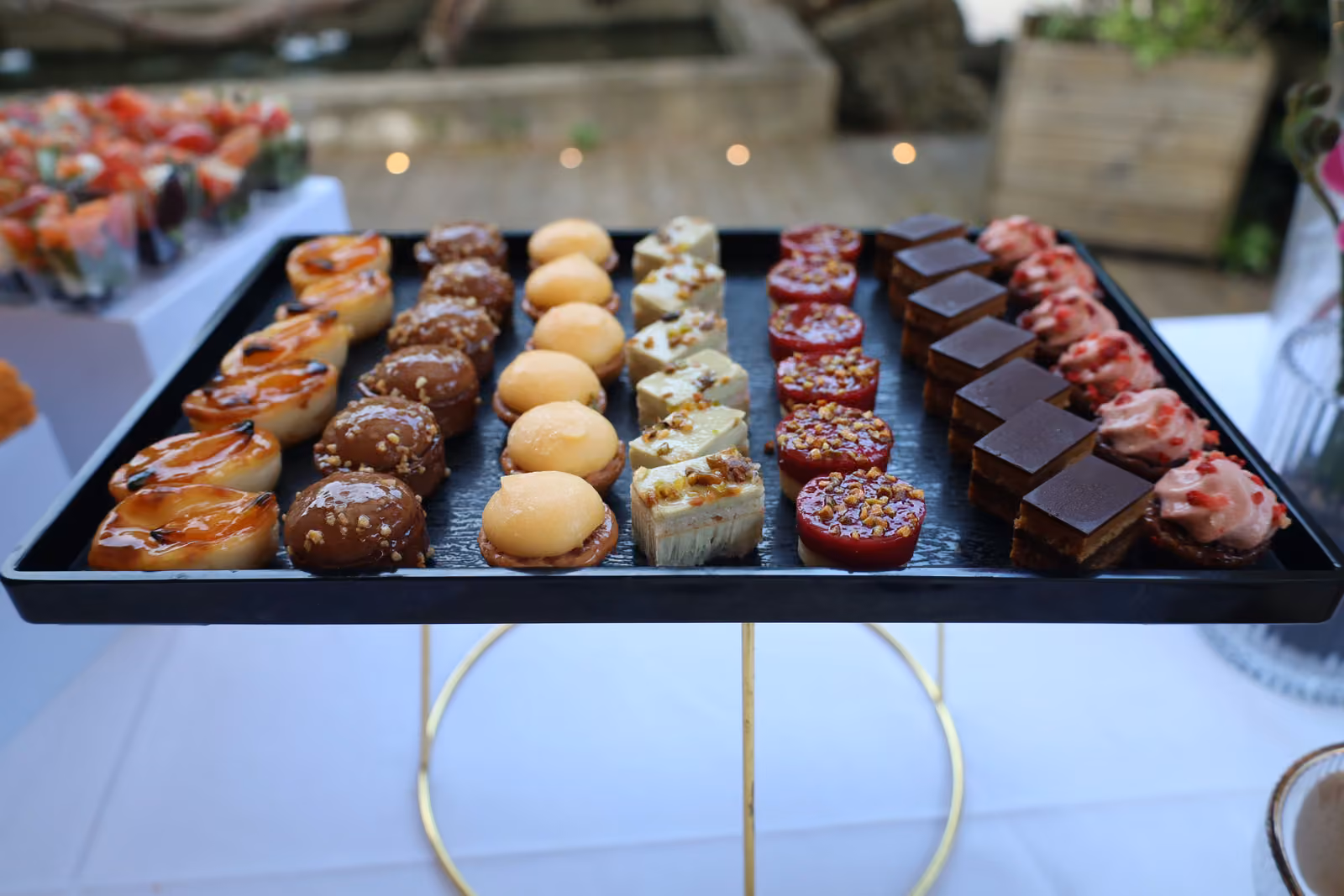 Plateau noir de mignardises : tartelettes, choux, carrés au chocolat et bouchées aux fruits rouges