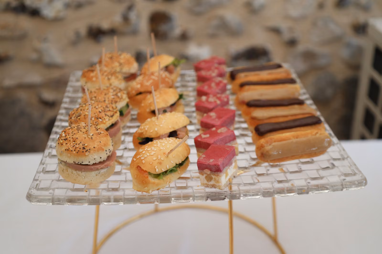 Plateau en verre de mini-burgers, gâteaux roses et éclairs au café pour un cocktail