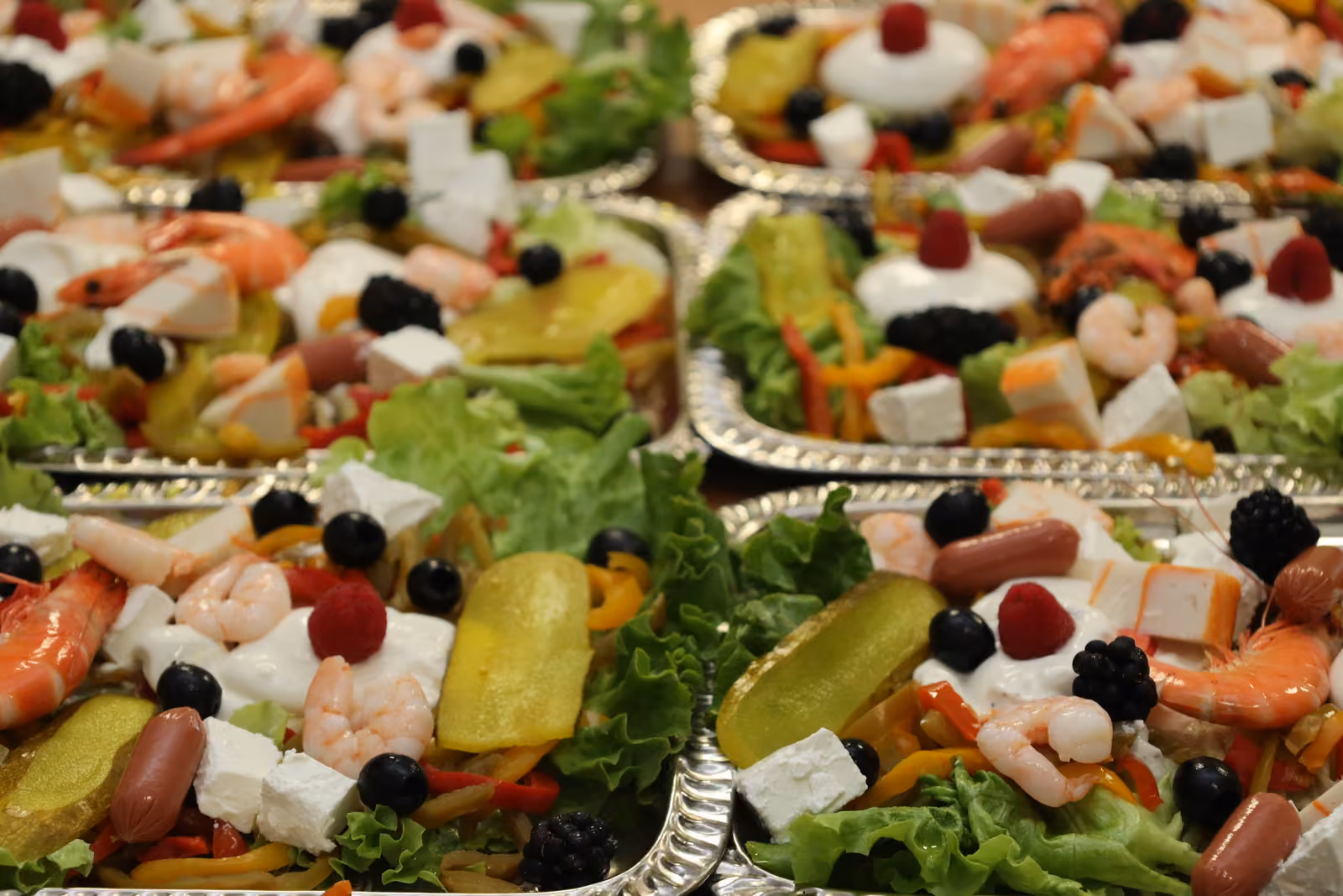 Gros plan d'une salade composée : crevettes, feta, olives, fruits rouges et poivrons