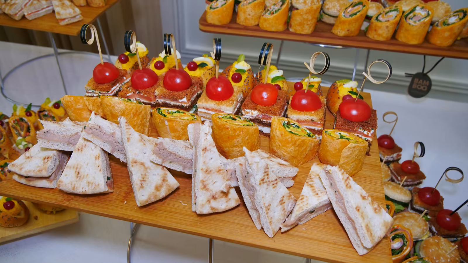 Plateau de sandwichs en triangle, wraps et bouchées à la tomate cerise sur présentoir