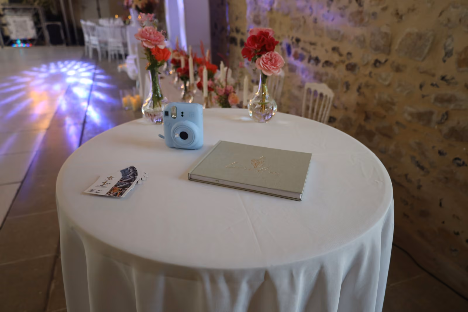 Table ronde du livre d'or de mariage avec appareil photo instantané bleu et roses rouges