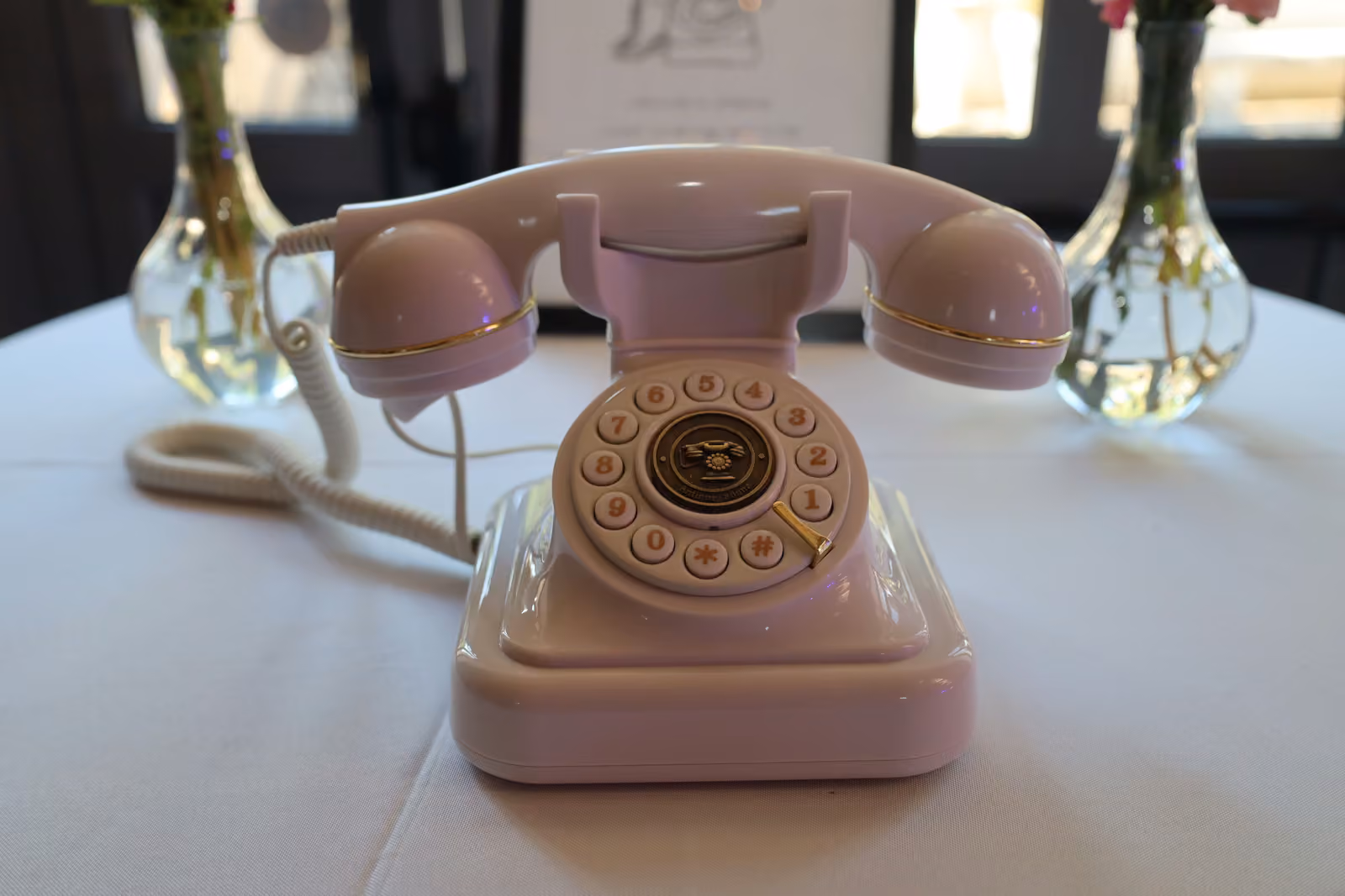 Téléphone rétro rose servant de livre d'or audio, posé sur une table de réception de mariage