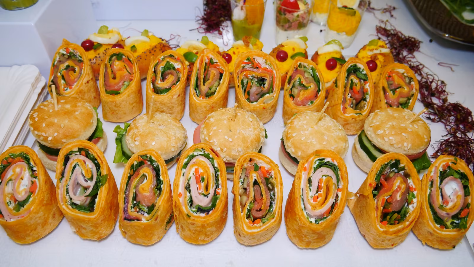 Wraps roulés au saumon et aux légumes alignés avec des mini-burgers